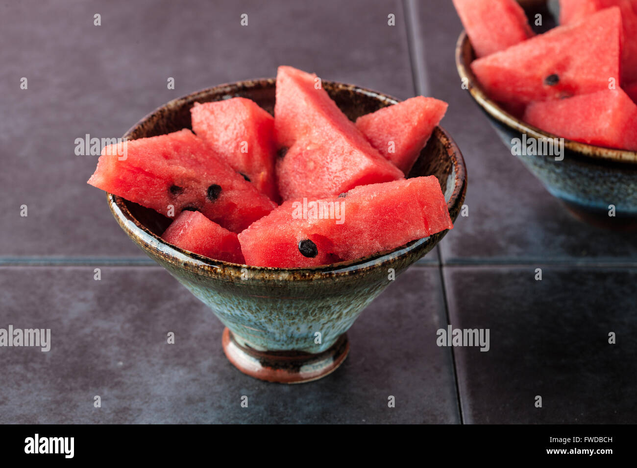 Triangle shaped watermelon slices placed in ceramic bowl on dark grungy background with copy space. Shallow depth of field. Stock Photo