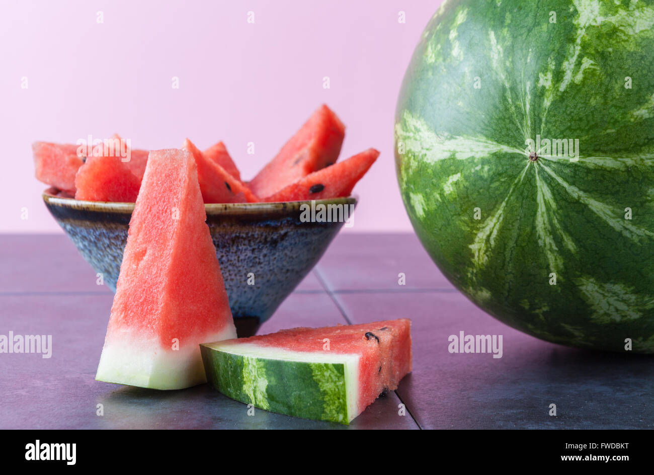 Whole watermelon and slices in ceramic bowl with copy space. Shallow depth of field. Stock Photo