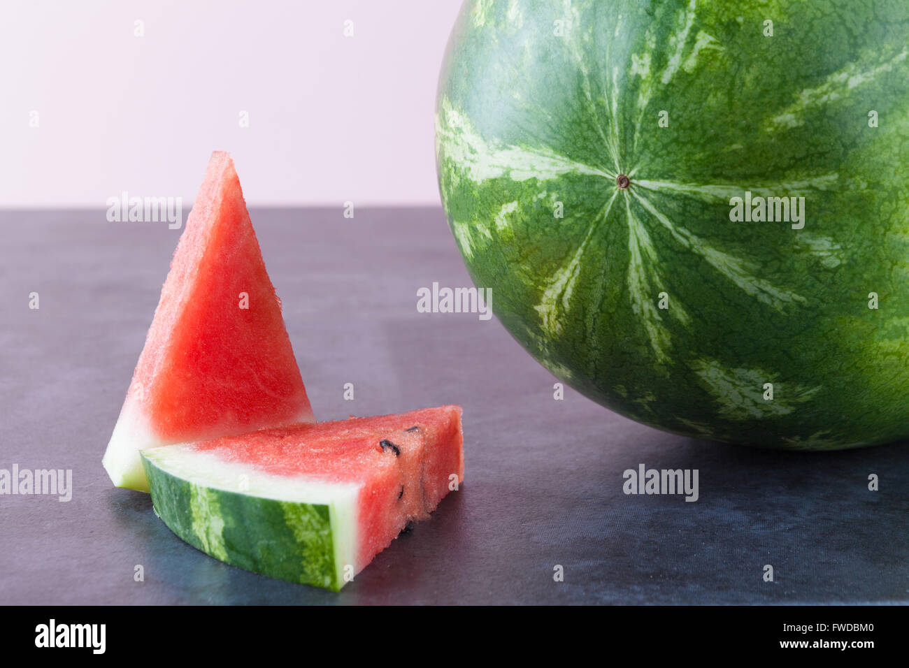 Whole and sliced watermelon on dark grungy surface with copy space. Shallow depth of field. Stock Photo