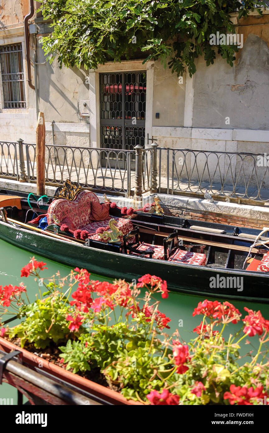 Colorful gondola and flowers on a picturesque side canal in Venice Stock Photo