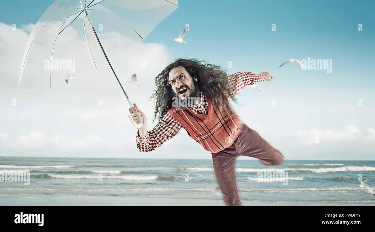 Funny guy holding a transparent umbrella on a beach Stock Photo Alamy