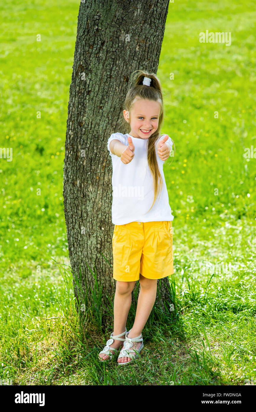 Smiling girl standing near a tree Stock Photo - Alamy