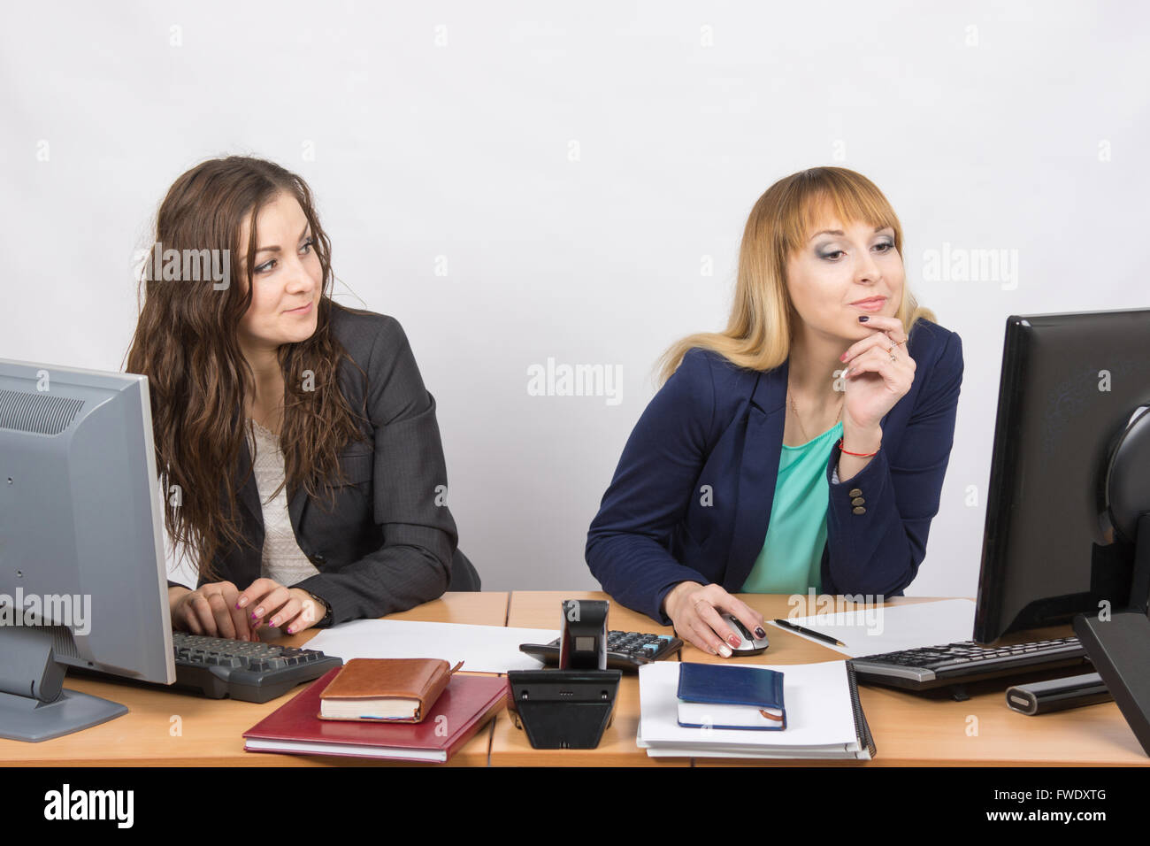 Office worker looking with distaste at the colleague sitting next to staring at a computer monitor Stock Photo