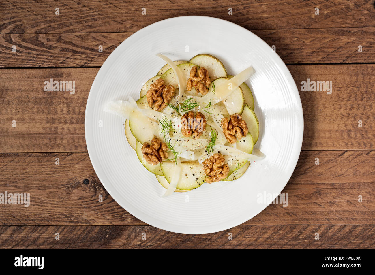 Plate of fennel, pear, walnut and Parmesan salad on a wooden board. Stock Photo