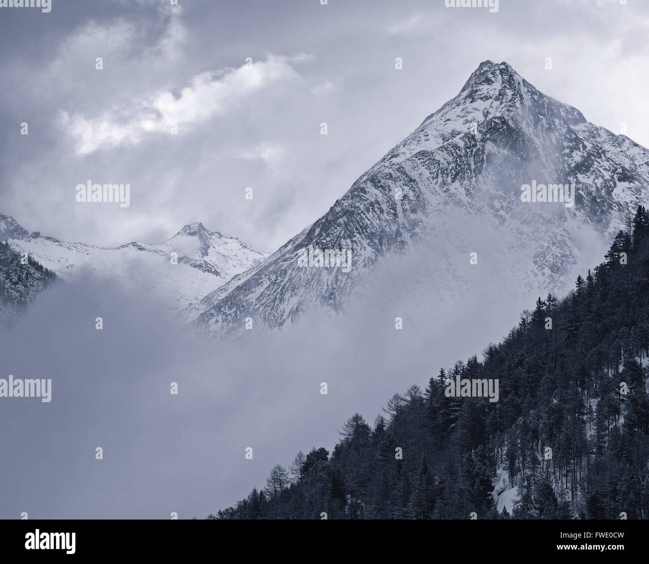 A B&W rendition of the high mountains above the Saas Fee resort in Switzerland on a misty winters day Stock Photo