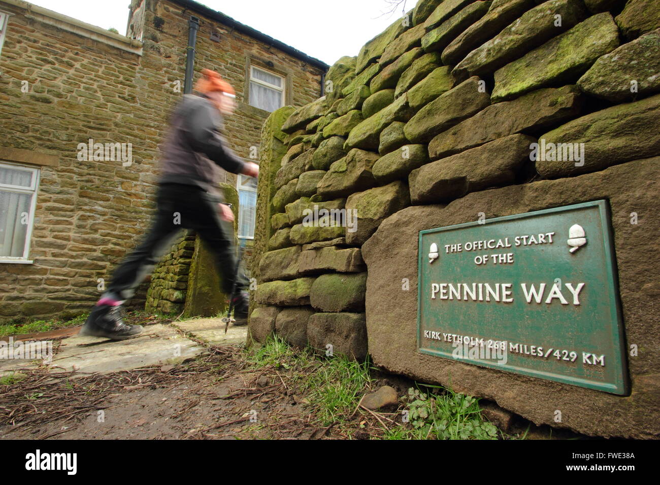 A walker passes the sign marking the official start of the Pennine Way at Edale in the Peak District National Park Derbyshire UK Stock Photo