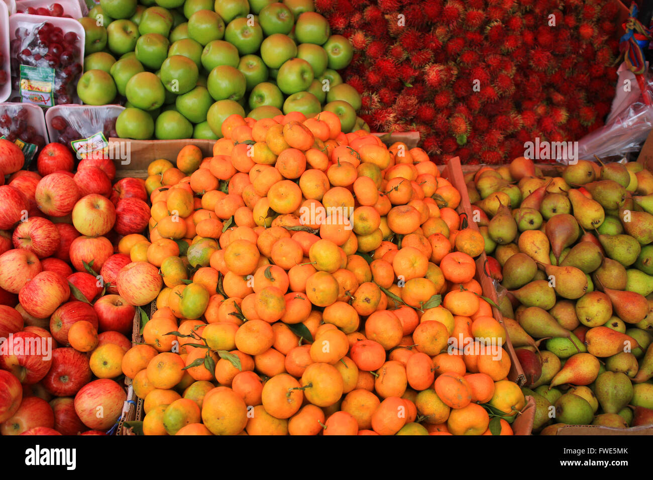 Fresh apples, rambutan, pears and oranges for sale at the outdoor food market in Otavalo, Ecuador Stock Photo