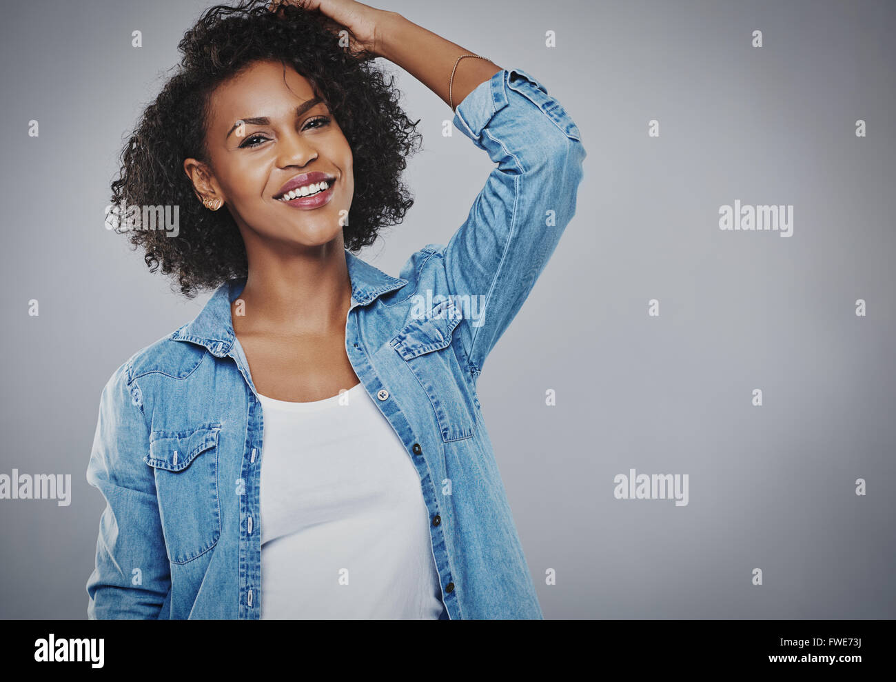 Happy vivacious young African American woman with curly hair standing ...