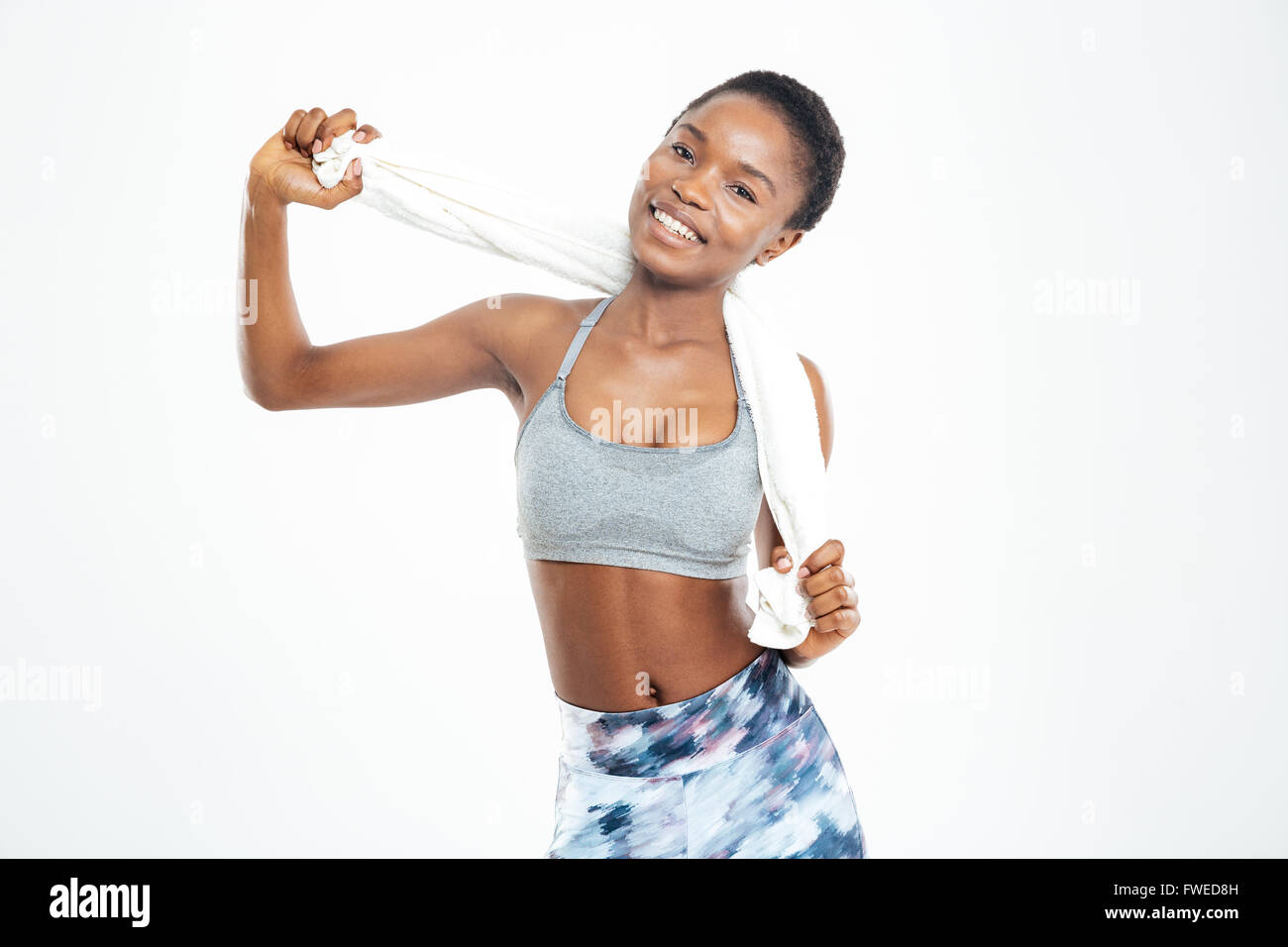 Happy lovely young african american sportswoman standing and posing with towel over white background Stock Photo