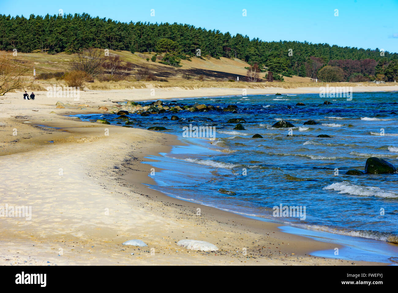 The breeze is whipping up some whites at the sea at the sandy stretch of coastline outside Kivik in Skane, Sweden. Two persons s Stock Photo