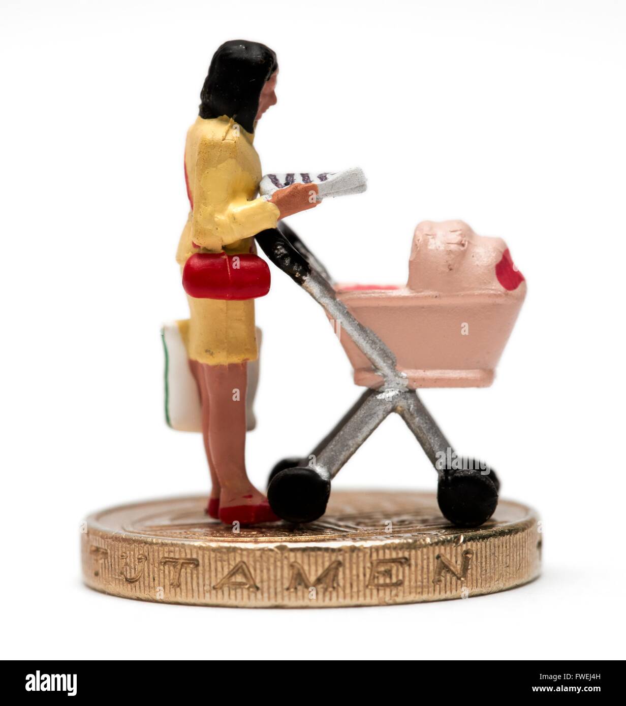 A single female miniature figurine parent with a pram standing on a pound coin Stock Photo