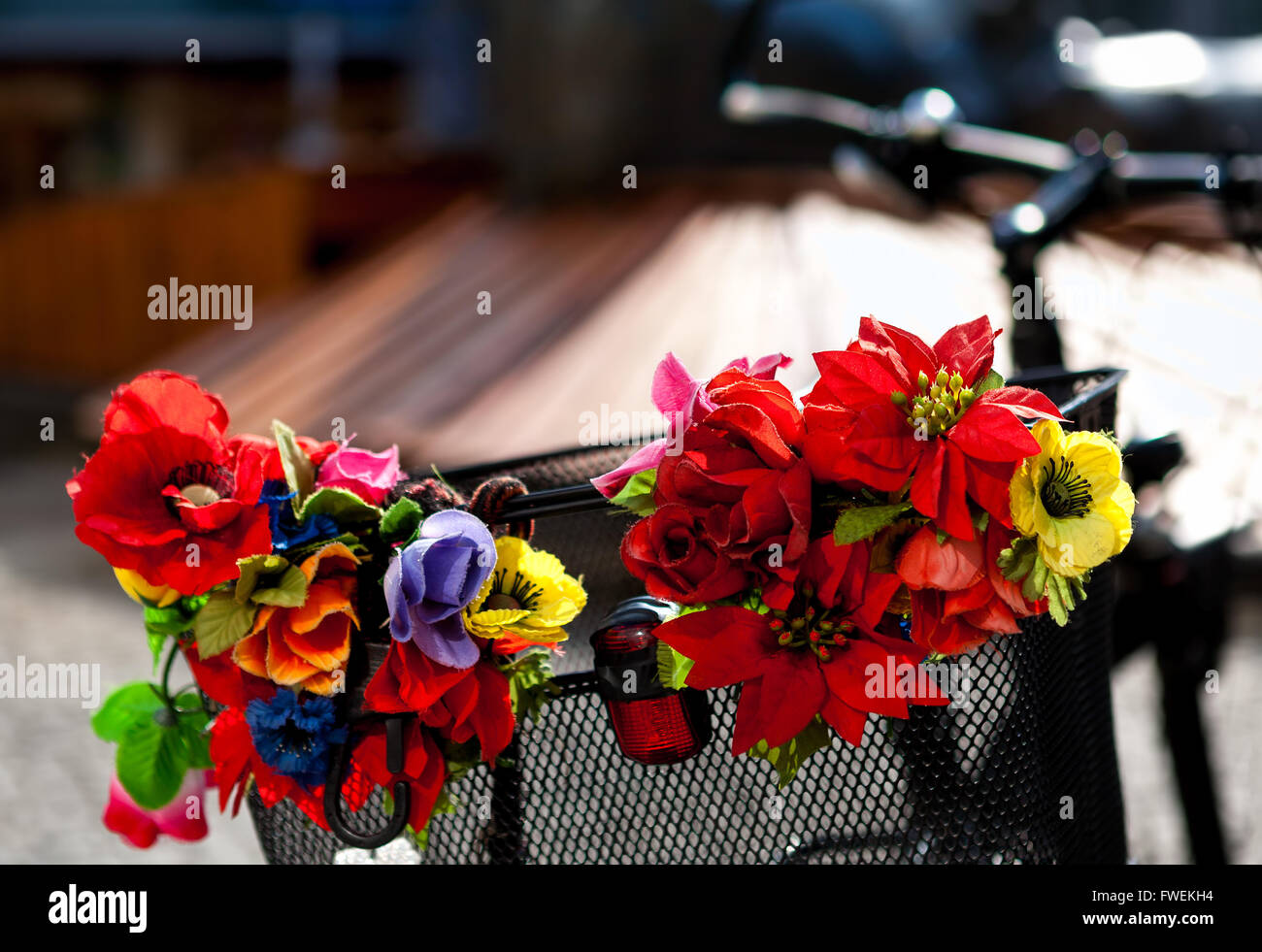 Artificial flowers on a metal bike basket Stock Photo