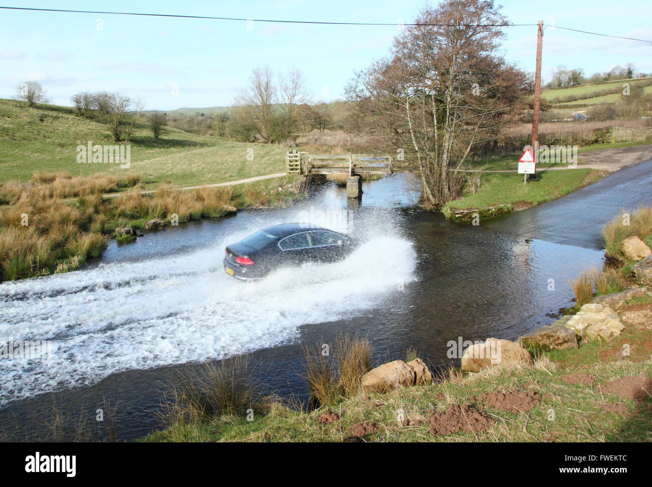 A car drives through Bradbourne Brook at the Tissington Ford at Tissington in the Derbyshire Dales, England UK Stock Photo