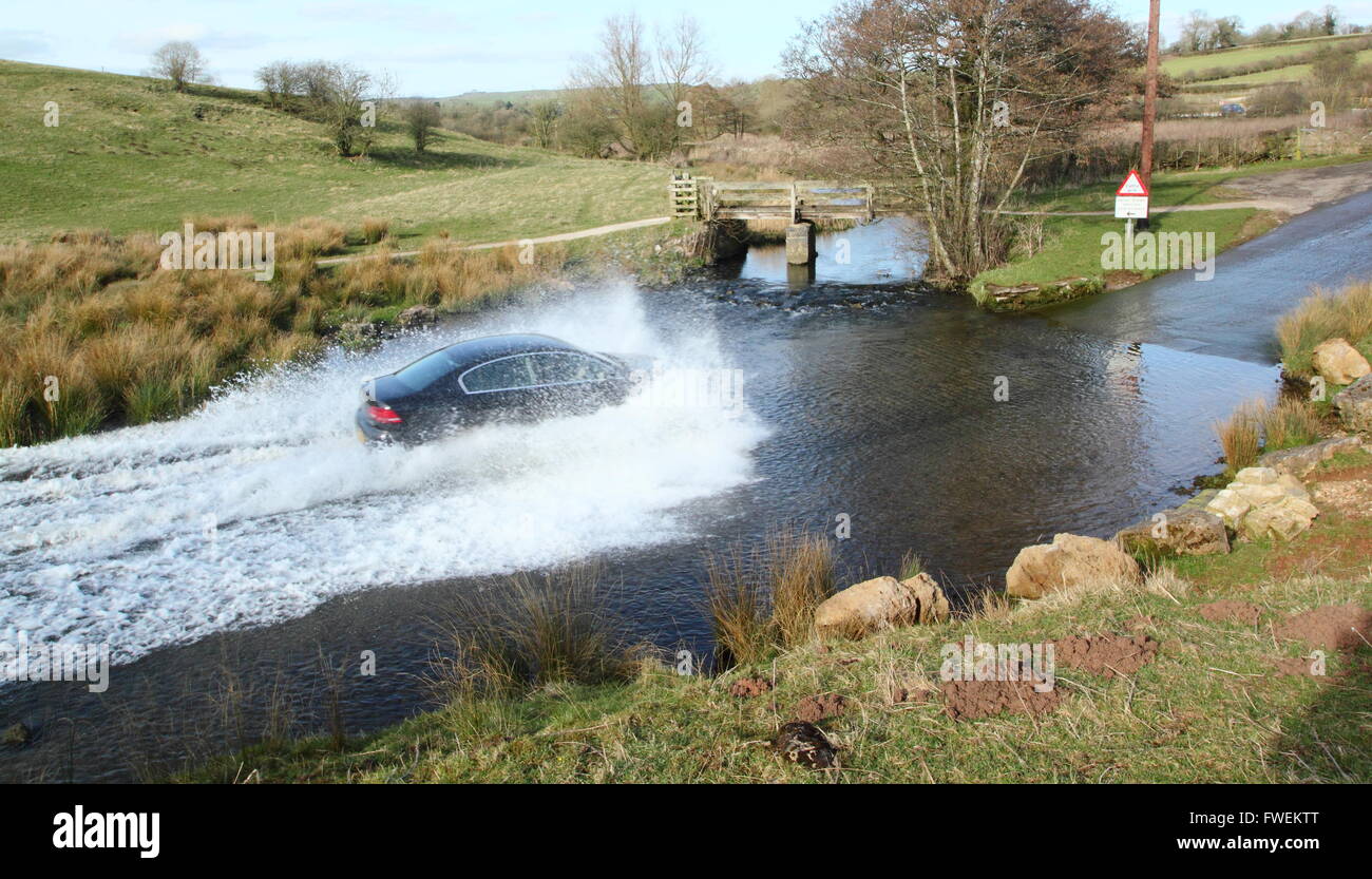 A car drives through Bradbourne Brook at the Tissington Ford at Tissington in the Derbyshire Dales, England UK Stock Photo