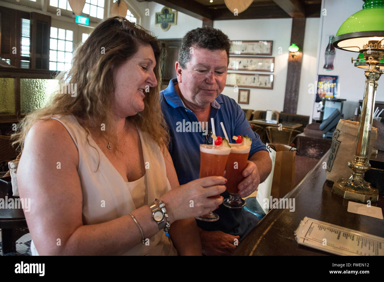 A couple of tourists enjoying their glass of 'Singapore Sling'  in the Long Bar at the Raffles Hotel in Singapore. Stock Photo