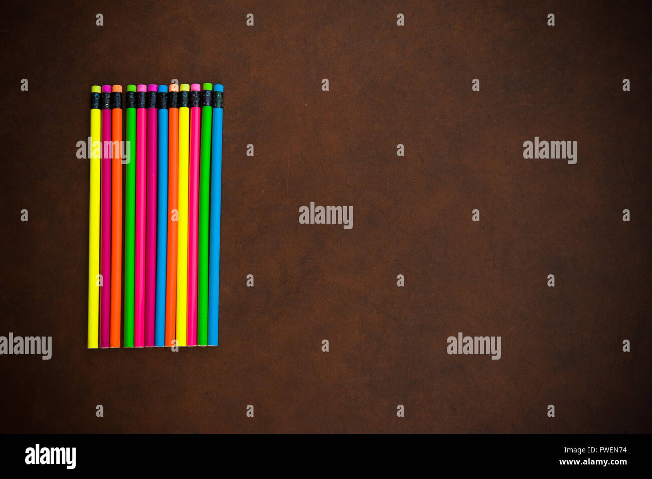 Wooden desktop with colorful pencil on the left side, red yellow, blue, green and purple Stock Photo