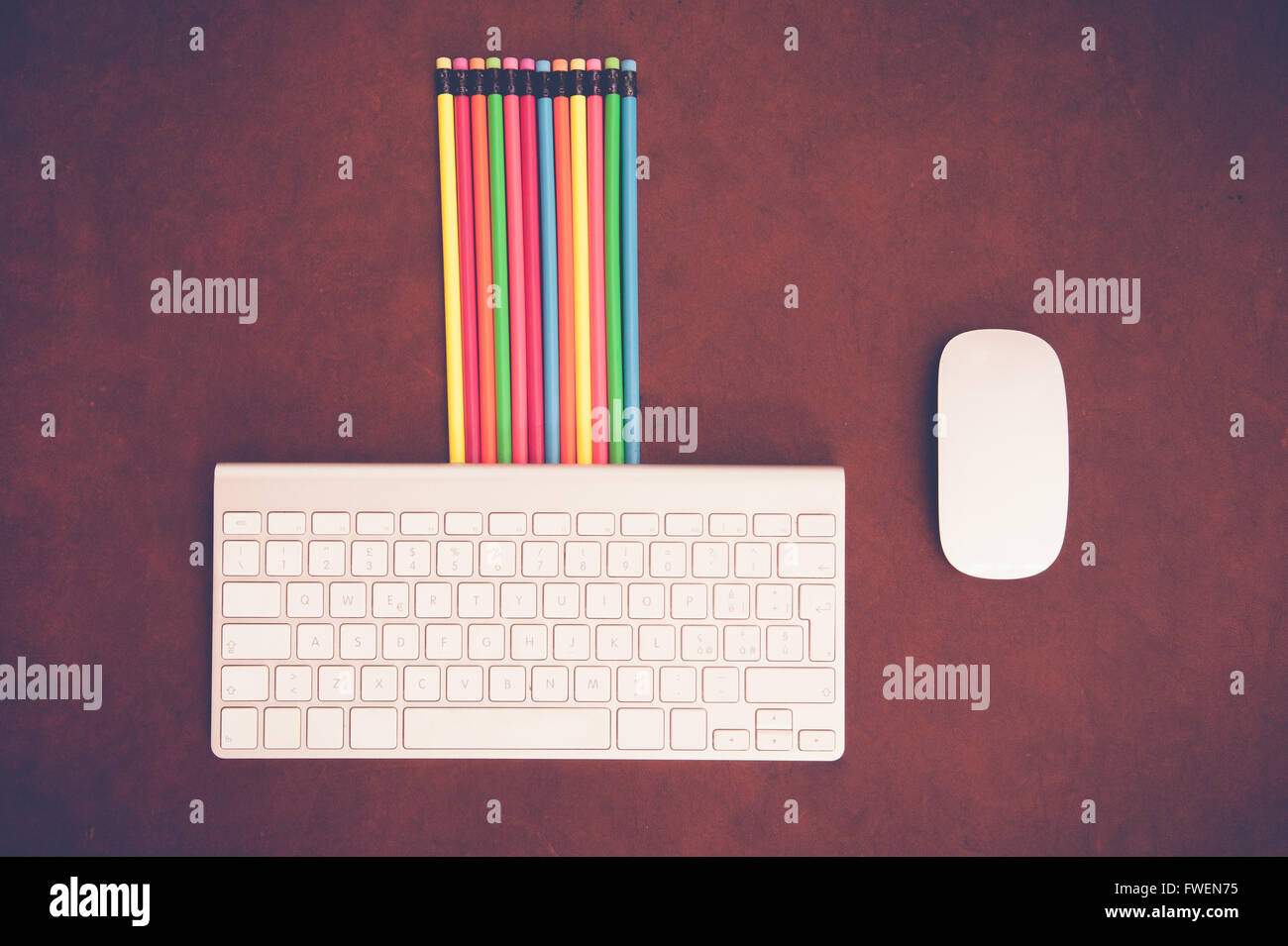 Wooden desktop with colorful pencil and computer keyboard and mouse Stock Photo