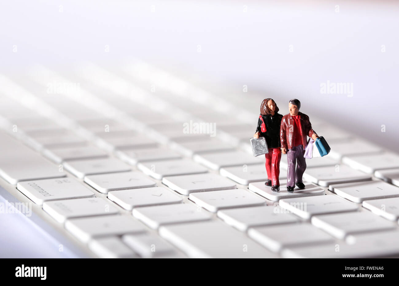 Online Shopping concept image of a couple on a computer keyboard carrying shopping bags Stock Photo