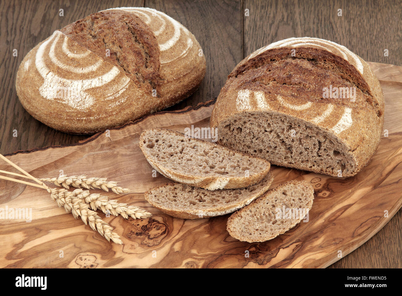 Crusty fresh homemade rye bread on an olive wood board with wheat