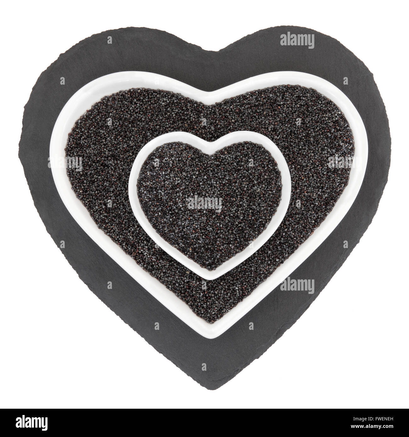 Poppy seed health food in heart shaped porcelain bowls on slate over