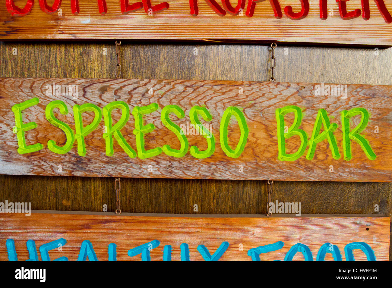 A handmade wood sign on a wood background is carved out and painted showing the words espresso bar in green letters. Stock Photo