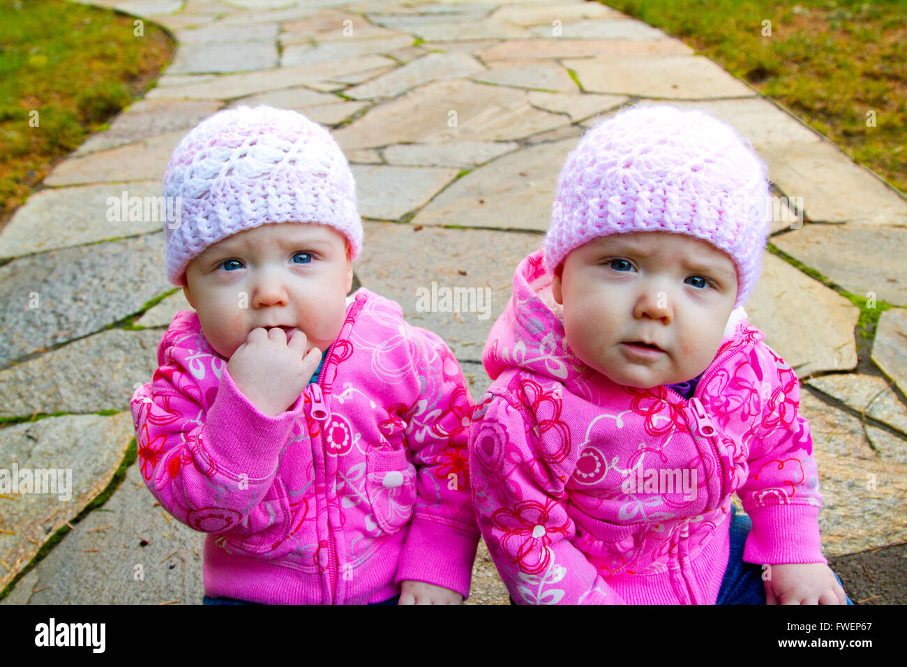 Two twin baby girls sit hi-res stock photography and images - Alamy