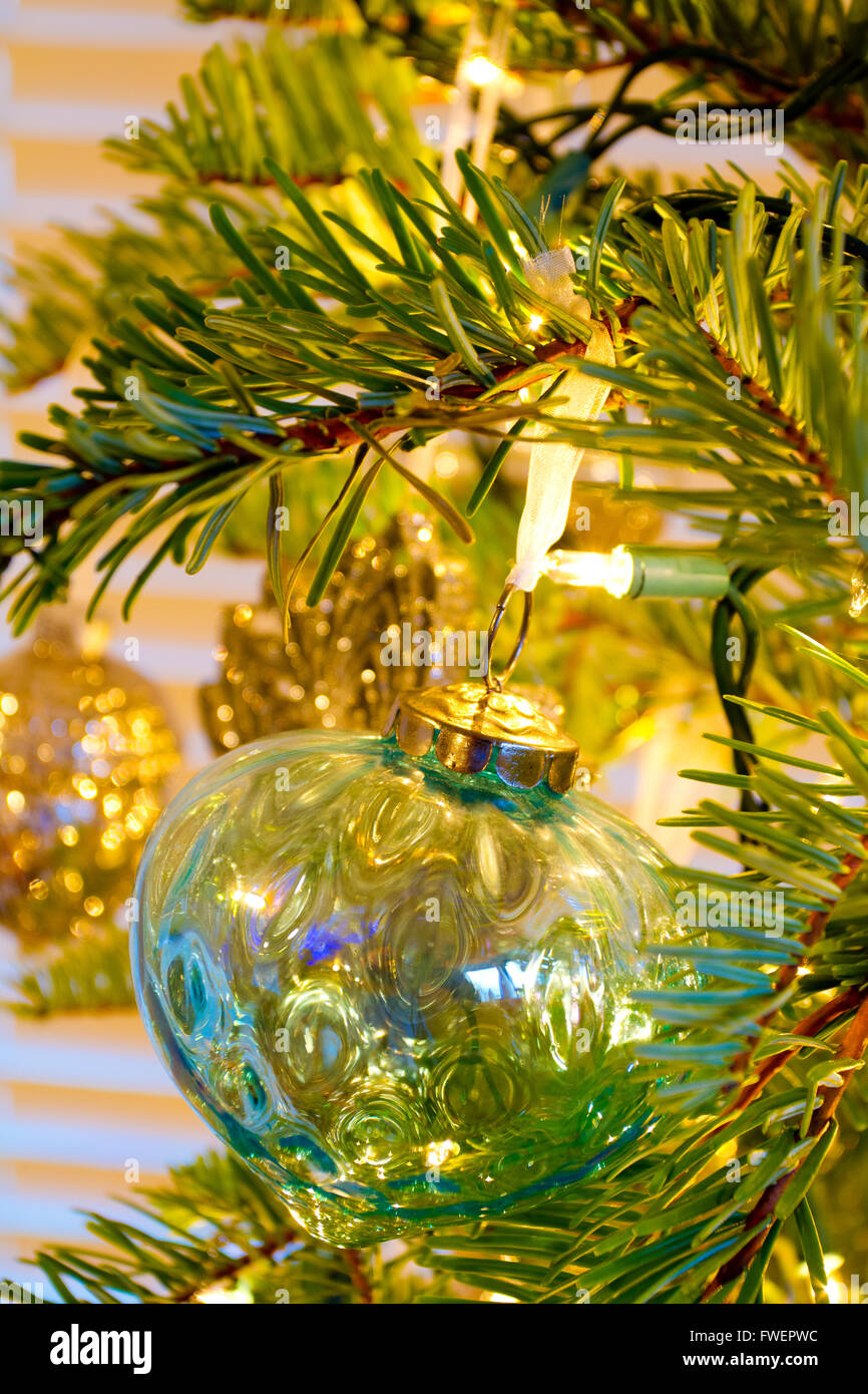 Elegant beautiful Christmas tree ornaments hang from this fir with lights and decorations all around. Stock Photo