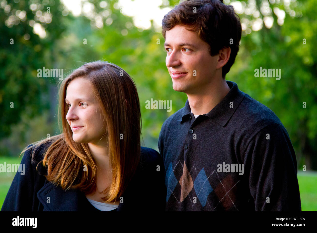A couple stands together for this portrait looking to the side. Stock Photo