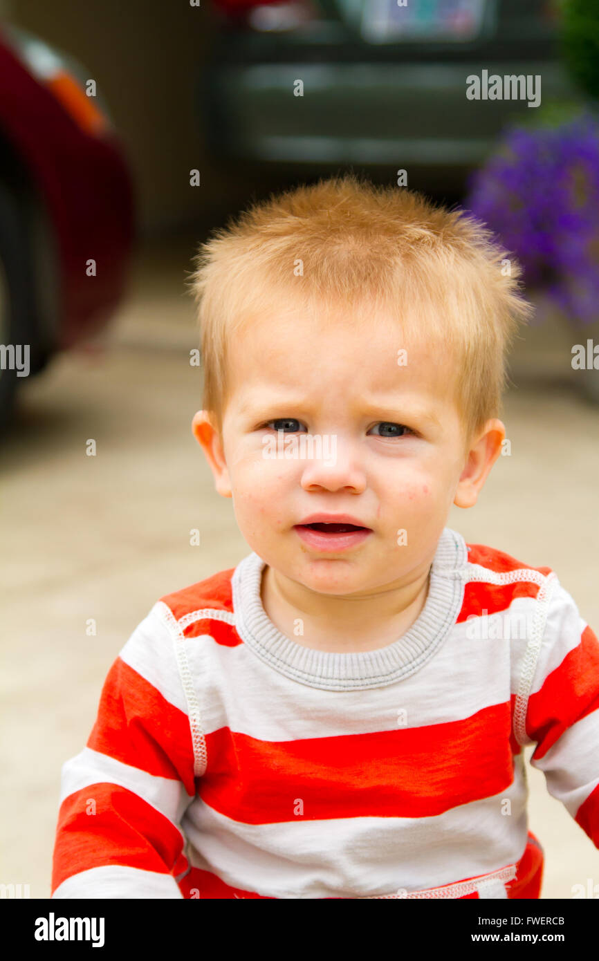 A portrait of a young boy playing outdoors wearing a red and white ...