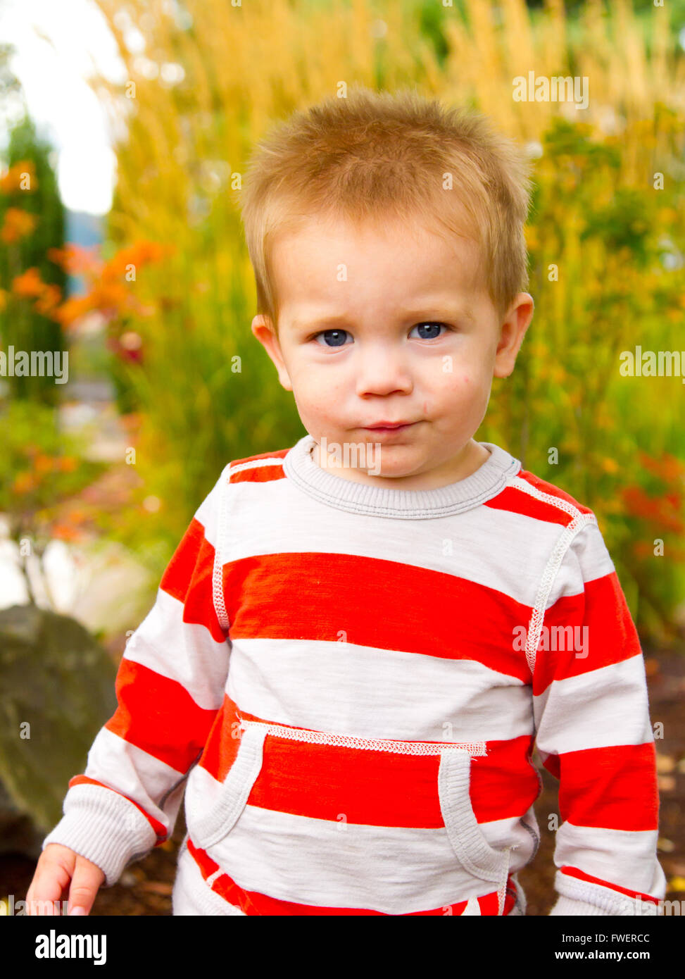 A portrait of a young boy playing outdoors wearing a red and white ...