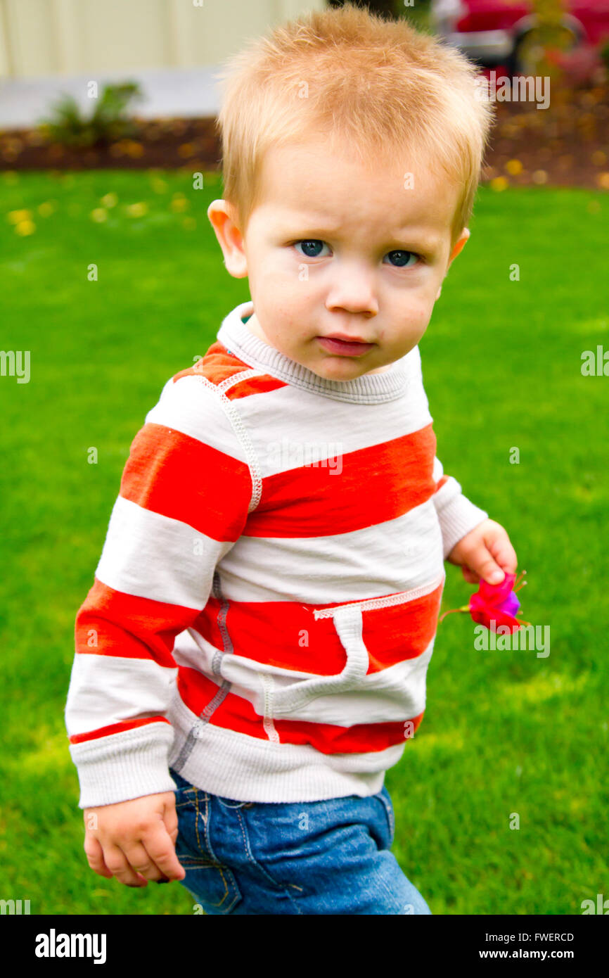 A portrait of a young boy playing outdoors wearing a red and white ...