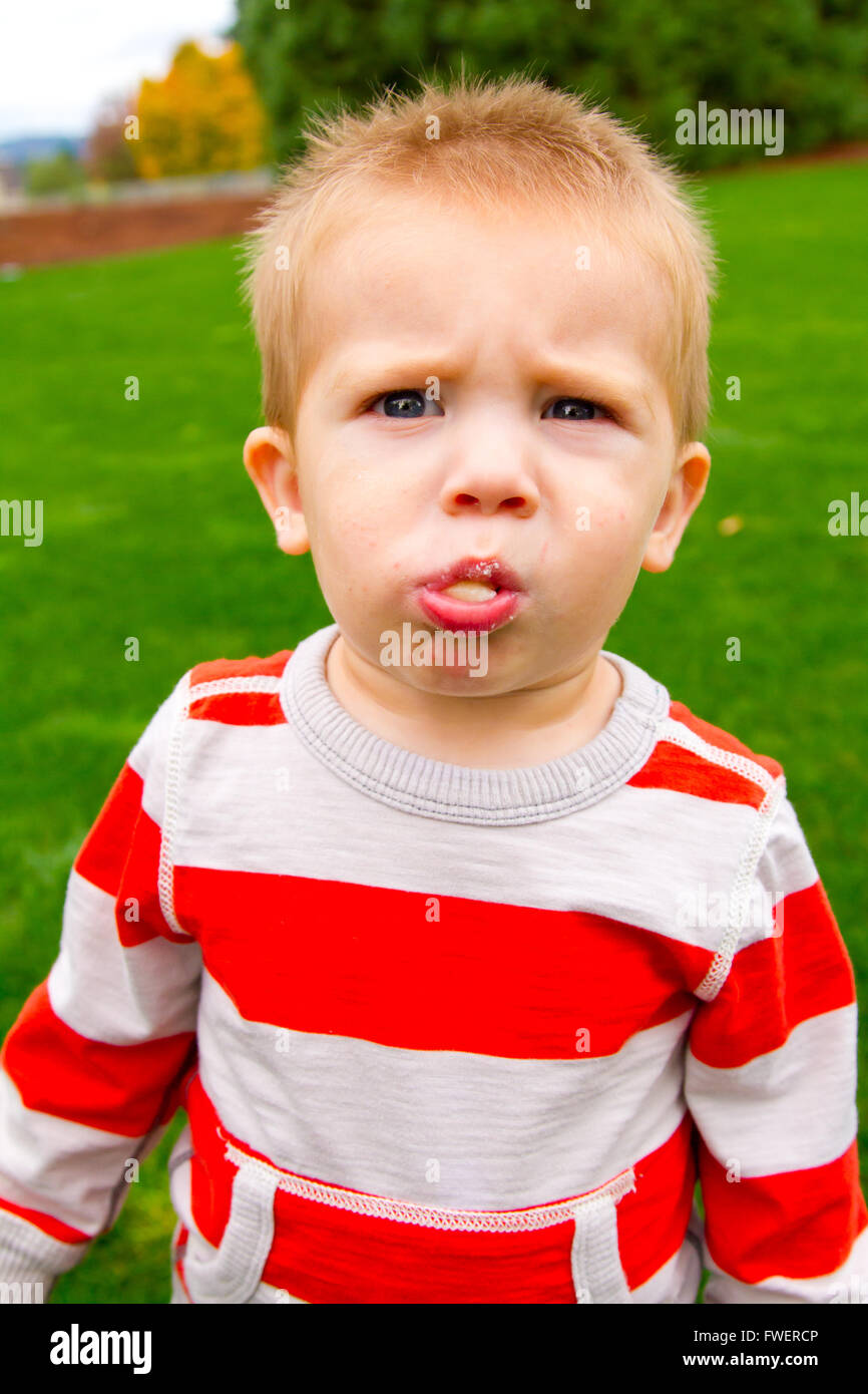 A portrait of a young boy playing outdoors wearing a red and white ...