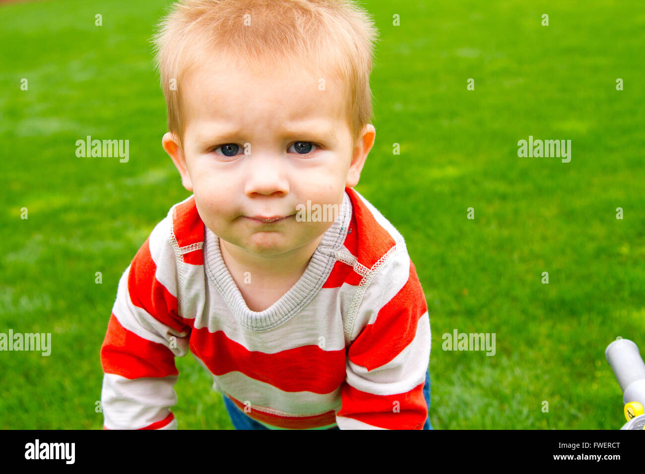 A portrait of a young boy playing outdoors wearing a red and white ...