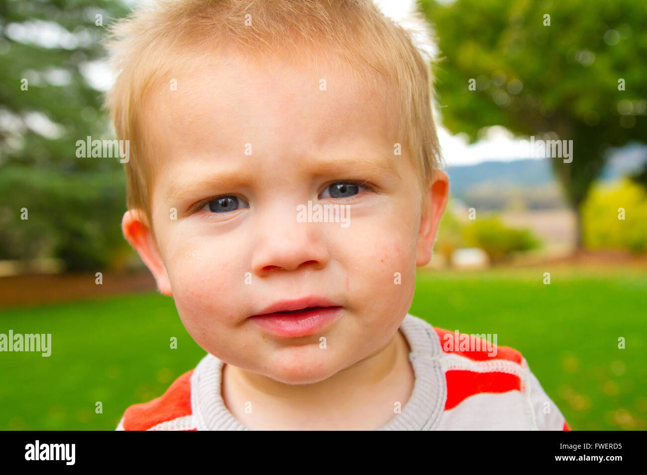A portrait of a young boy playing outdoors wearing a red and white ...