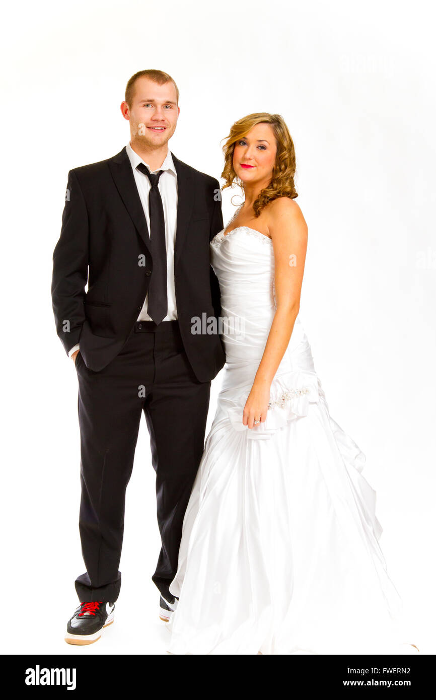Bride and groom in a studio with a white background pose for a
