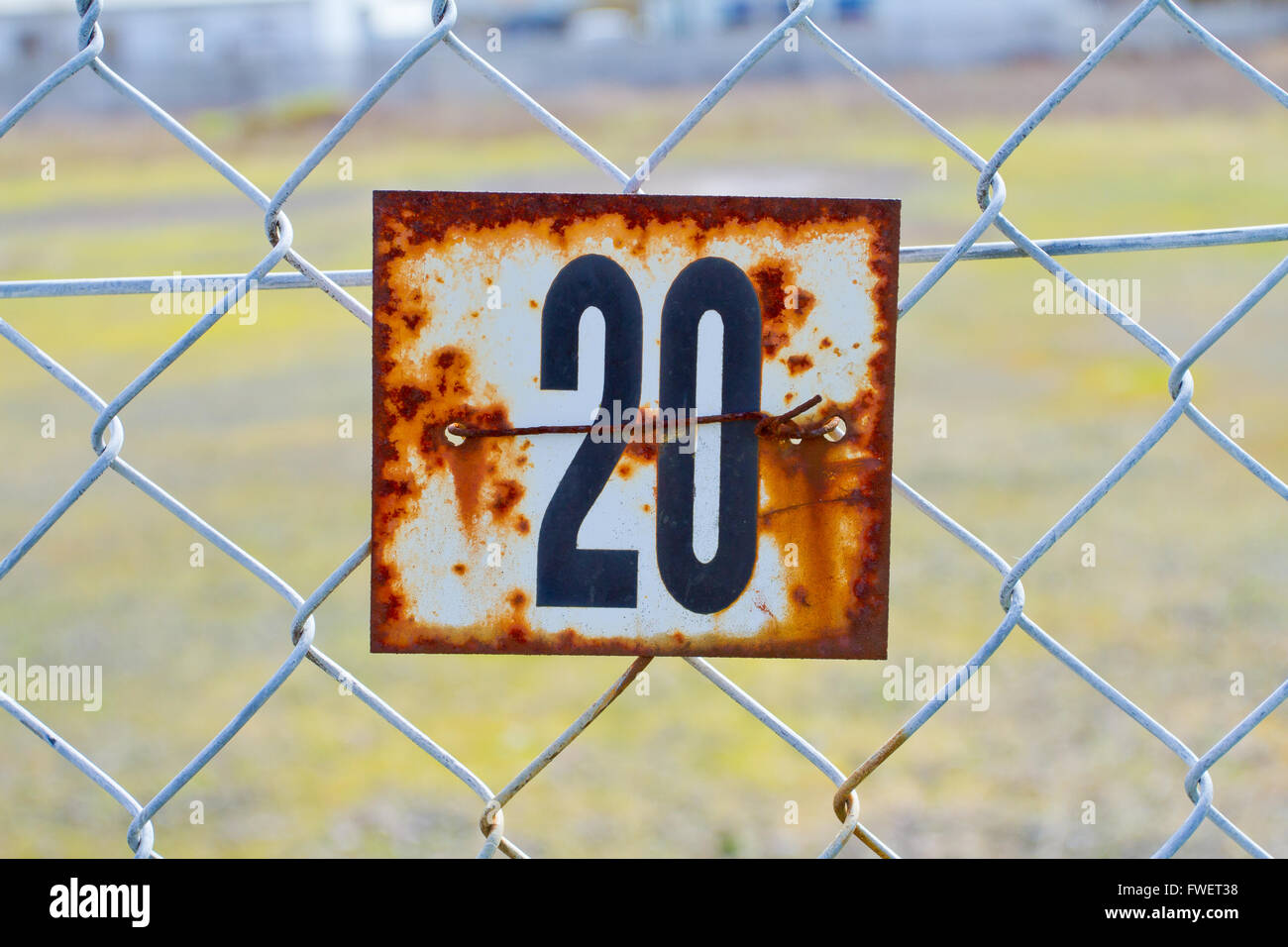 A series of rusted old signs or tags are attached to this chain link fence with orange and white rust and the numbers clearly vi Stock Photo