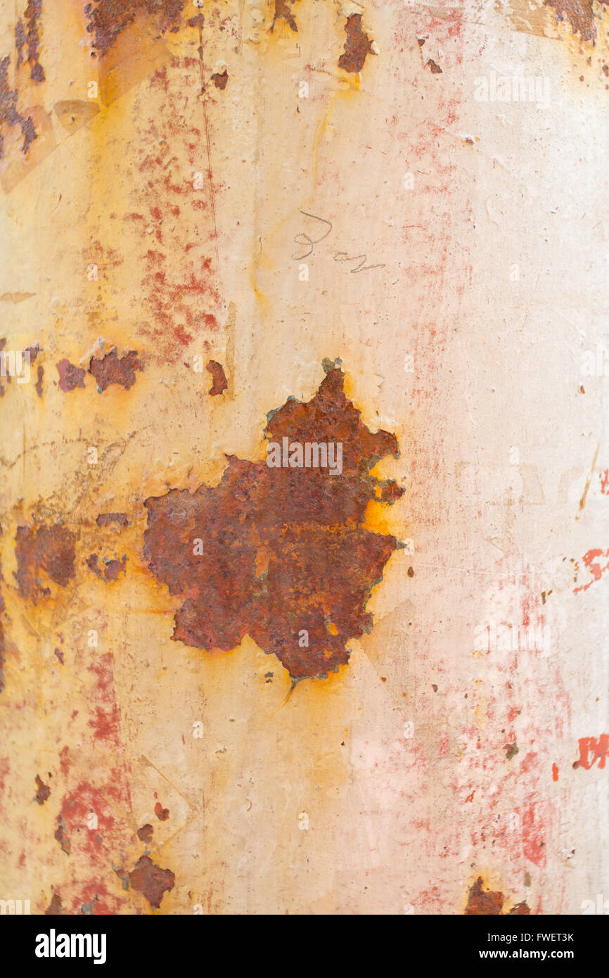 Paint peels off this rusty weathered pole showing some muted tones of white pink orange and red