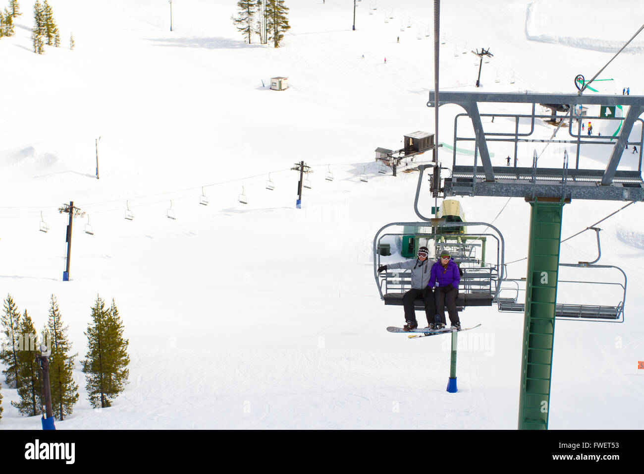 A couple of people ride the ski chair lift up the mountain together