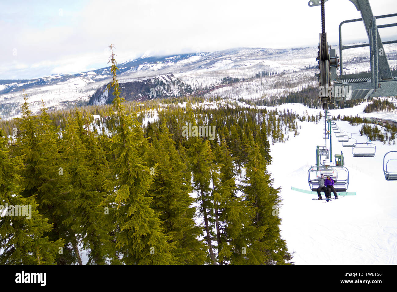 A couple of people ride the ski chair lift up the mountain together