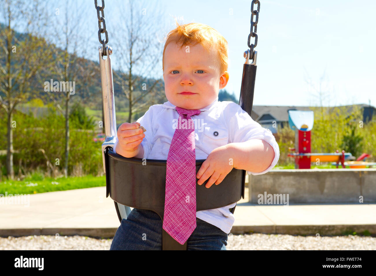 A Baby Boy Plays On A Swing Set At The Park Wearing Nice