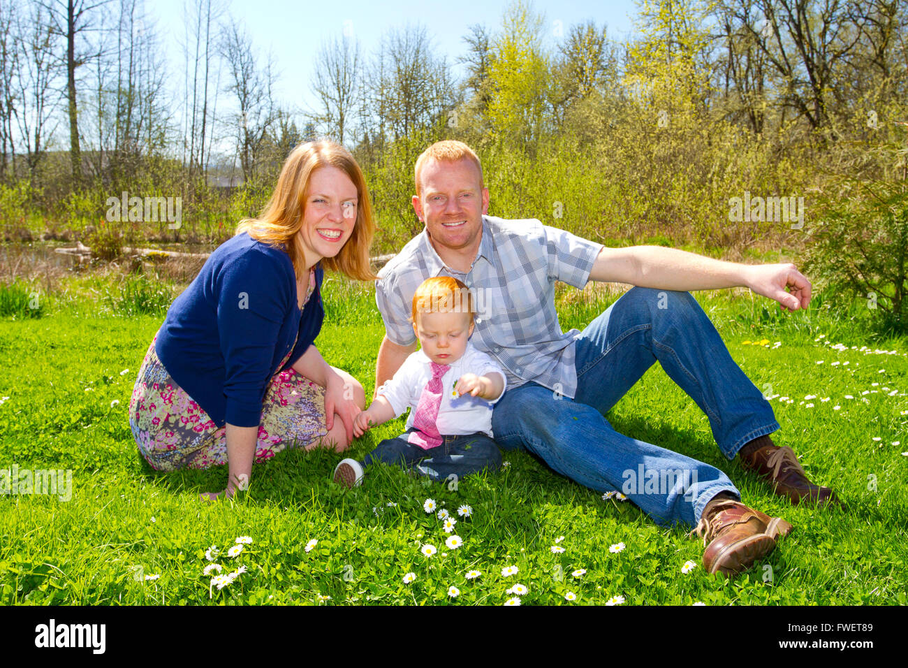 A mom and dad with their one year old baby boy at a nice park wearing trendy clothes. Stock Photo