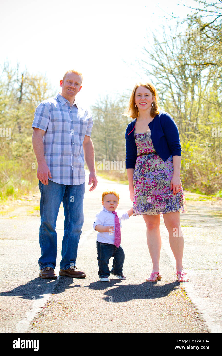 A family of three people together outdoors wearing nice clothes in this simple portrait. Stock Photo