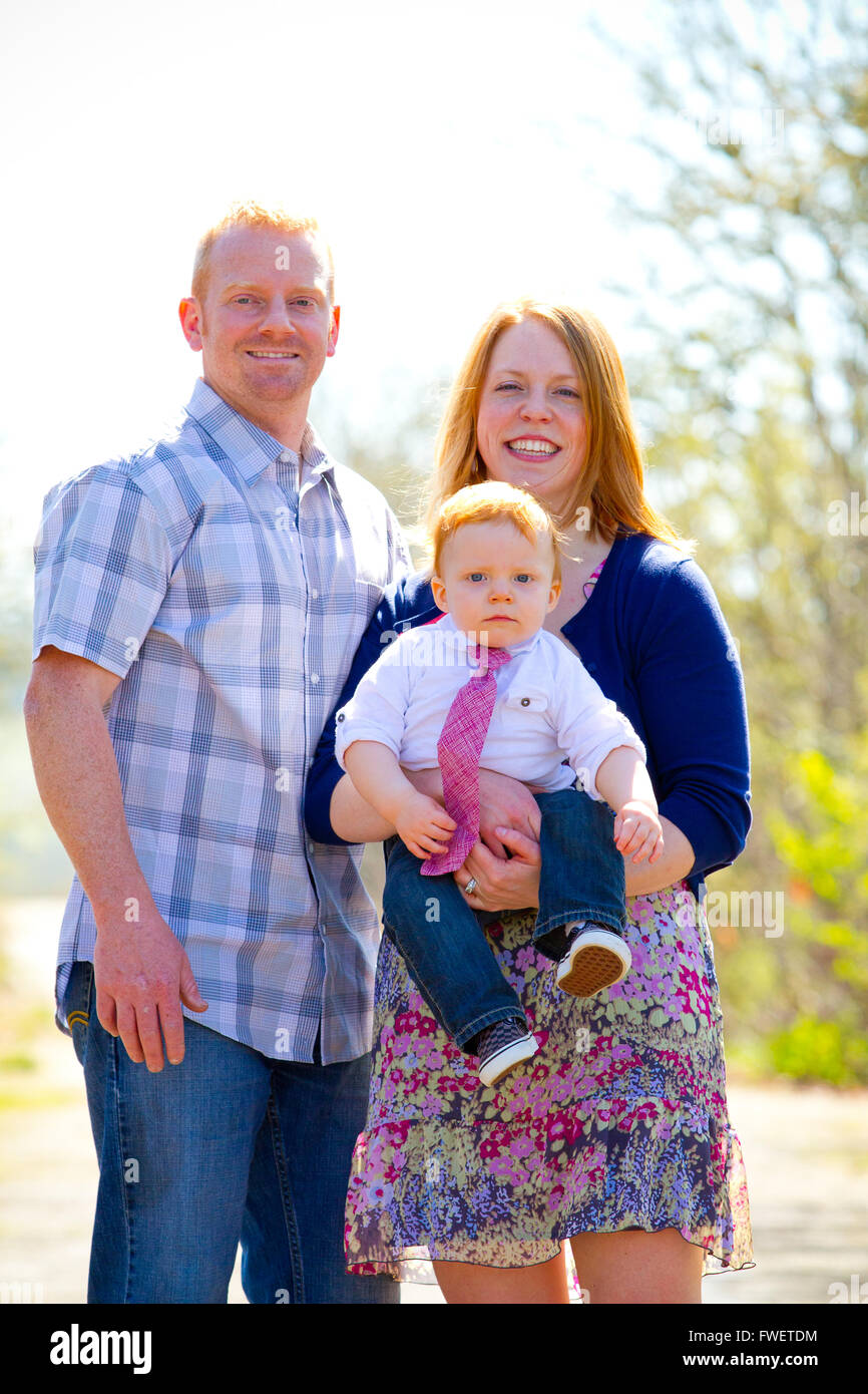 A family of three people together outdoors wearing nice clothes in this simple portrait. Stock Photo