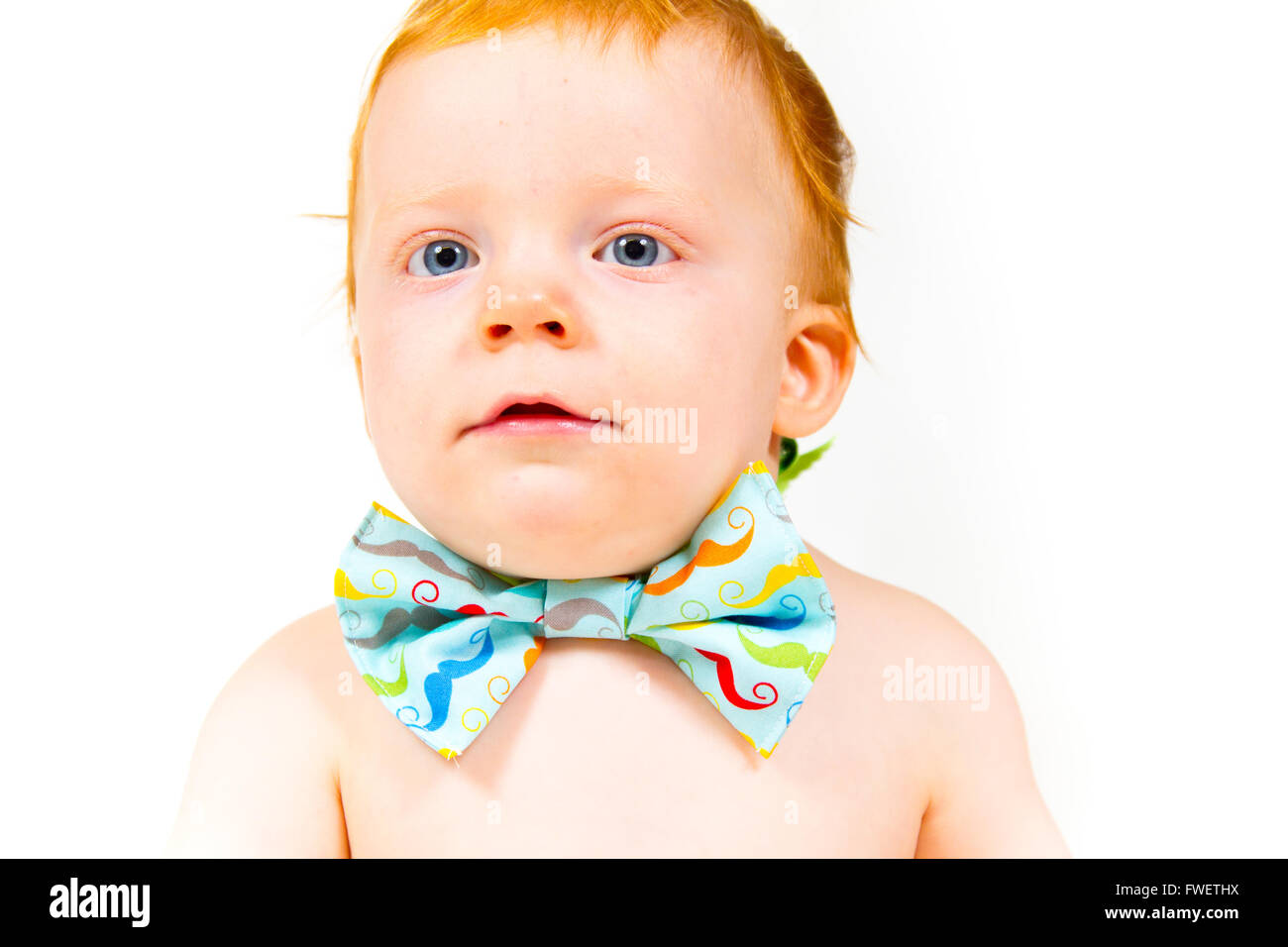 A one year old baby boy in the studio with a white background. The kid is wearing a bowtie and a diaper. Stock Photo
