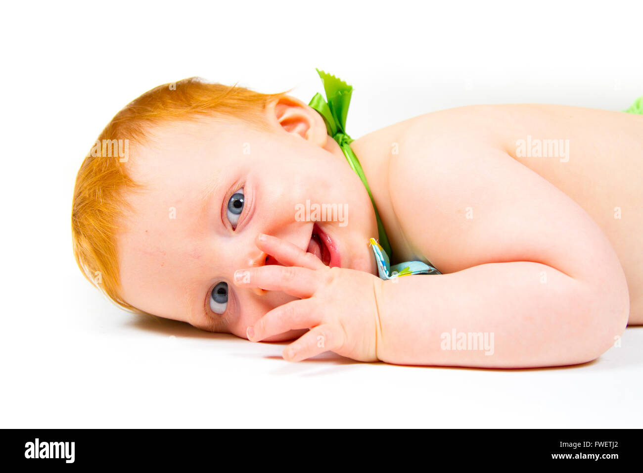 A cute one year old boy lays in the studio against a white background looking cute and happy. Stock Photo