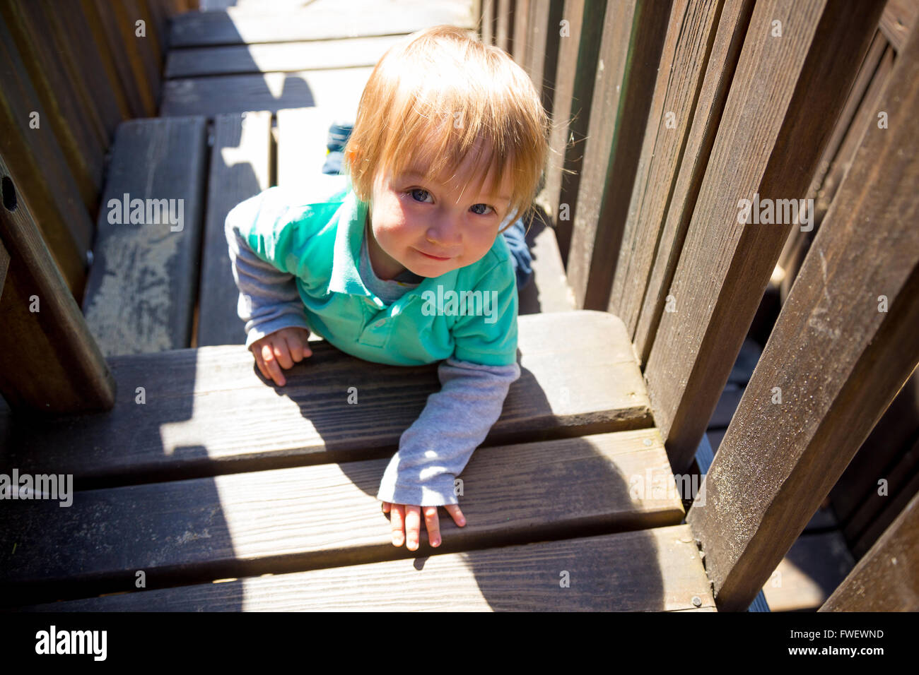 A cute young boy climbs the wooden stairs at a playground in a park in Lincoln City Oregon. Stock Photo