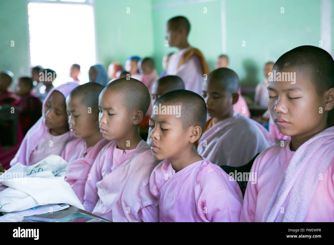 Buddhist novice schoolgirls conducting class meditation in the school classroom before lessons, Sagaing, Myanmar, Southeast Asia Stock Photo