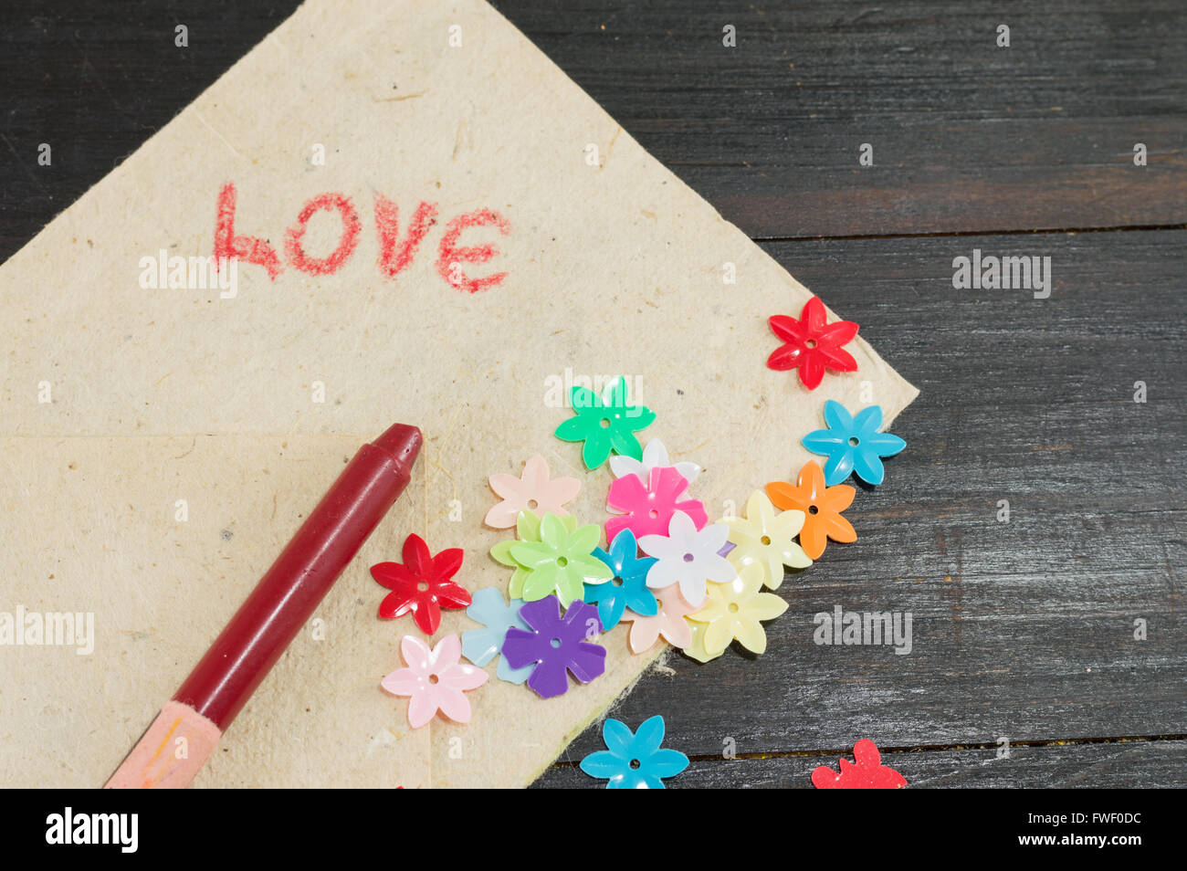 handwritten word love on paper with artificial flowers Stock Photo