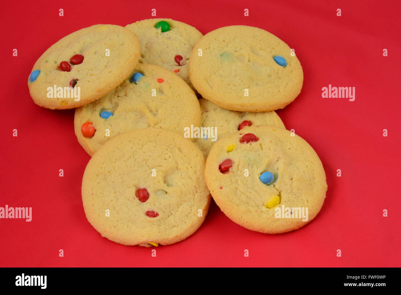 Sugar cookies with candy coated chocolate in red background Stock Photo