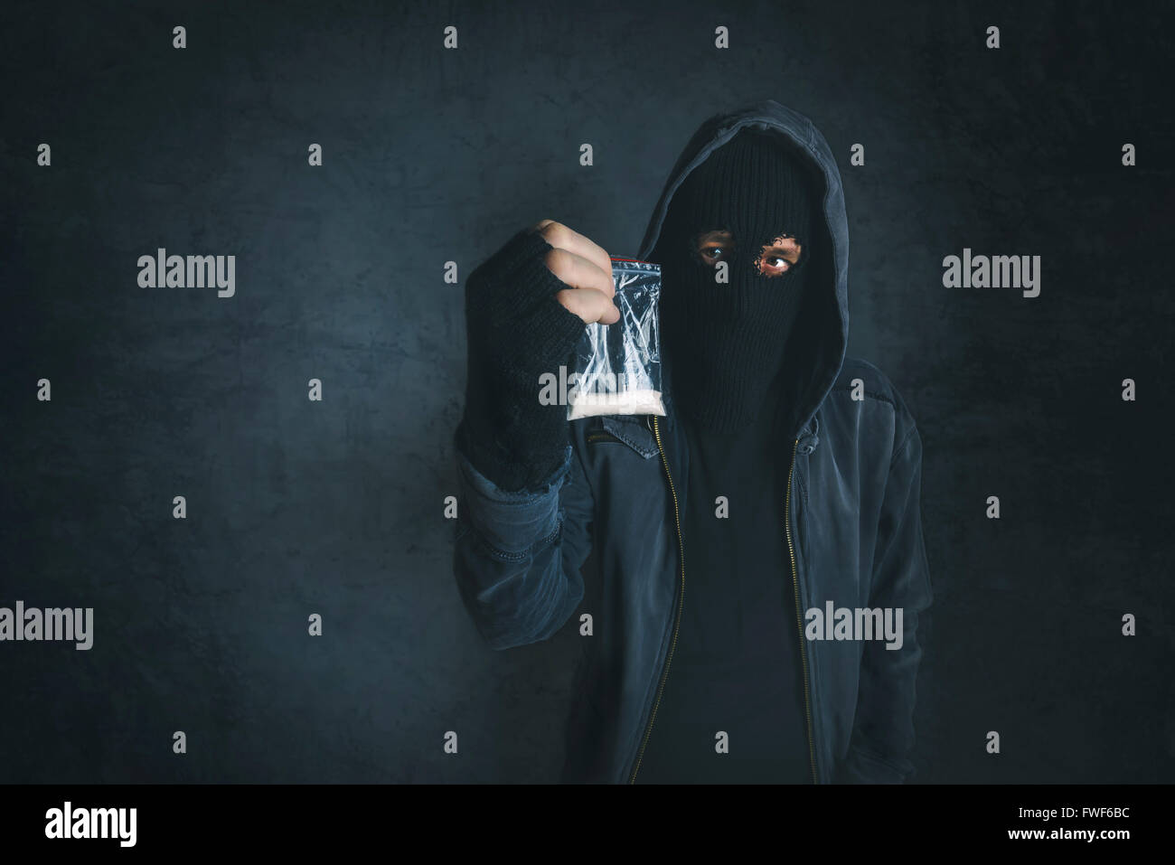 Drug dealer offering narcotic substance to addict on the street, unrecognizable hooded criminal selling drugs in dark alley Stock Photo